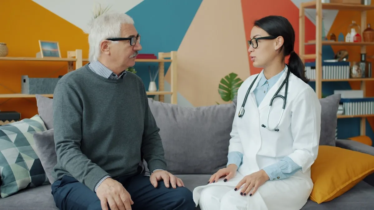 A caring doctor talks with an older patient at home